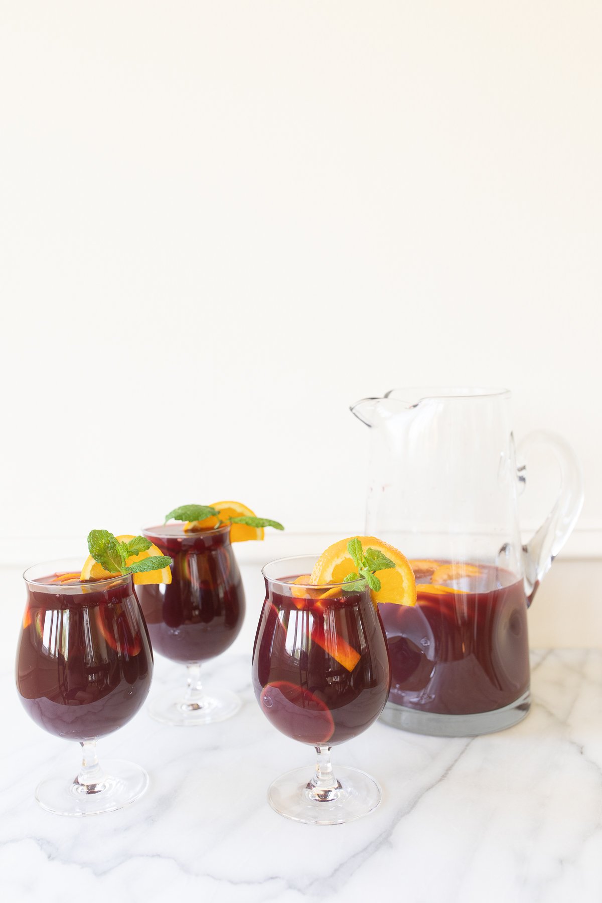 Traditional red sangria in stemware, garnished with fresh mint and orange slices.