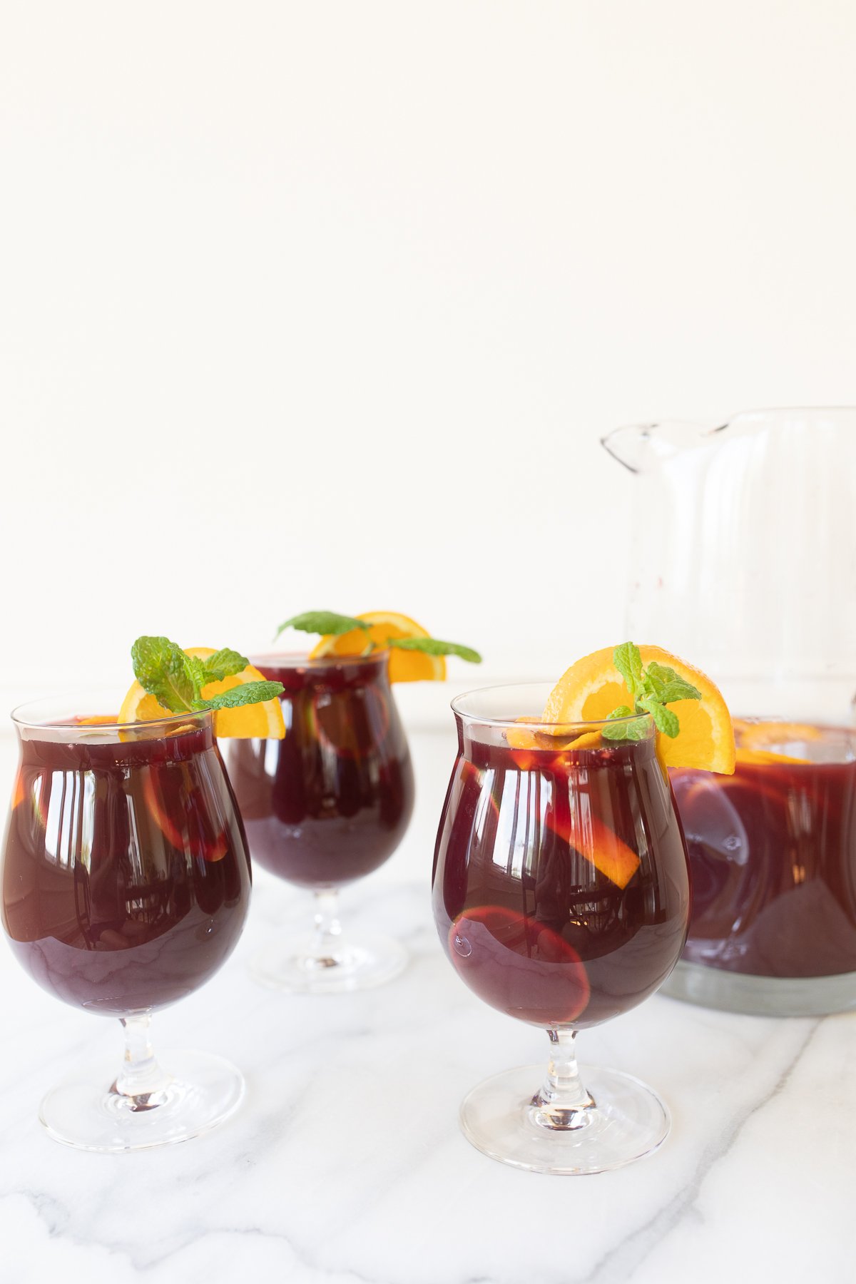 Traditional red sangria in stemware, garnished with fresh mint and orange slices.