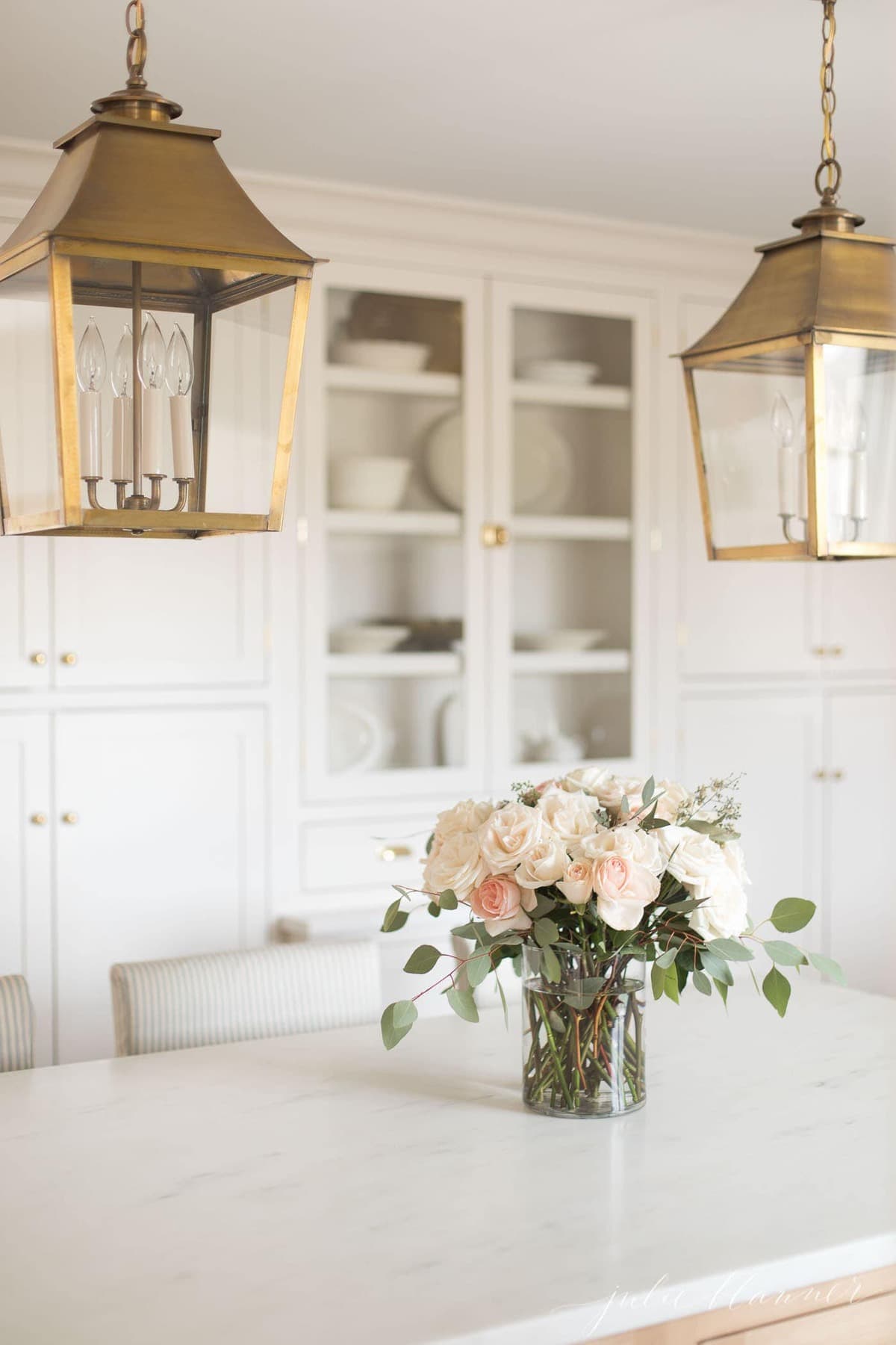 Flowers in a glass vase on a marble kitchen countertop. 