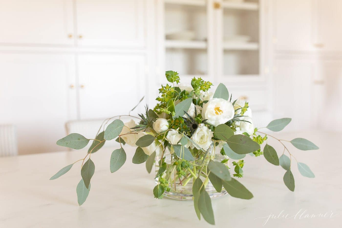 Flowers in a glass vase on a marble kitchen countertop. 