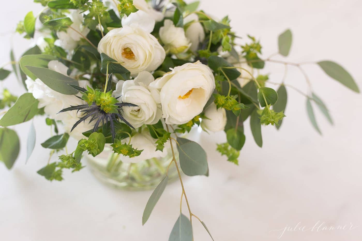 Flowers in a glass vase on a marble kitchen countertop. 