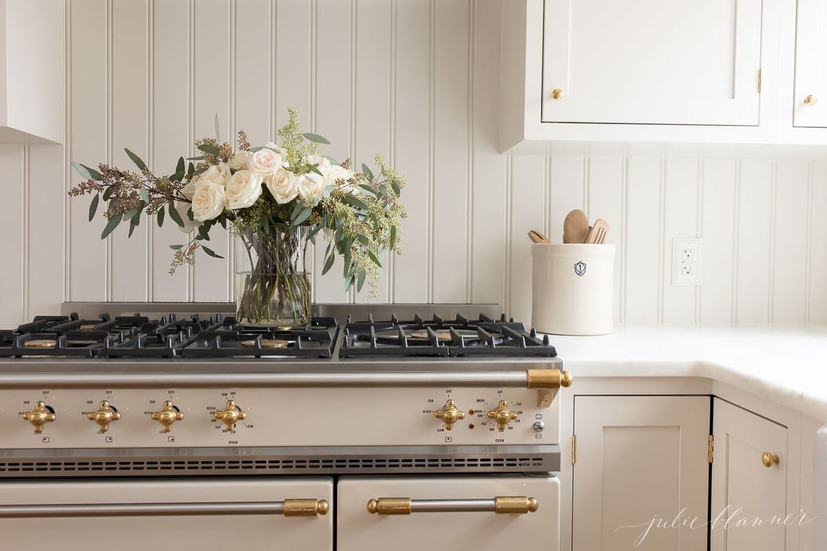 Roses in a glass vase on a kitchen stovetop. 