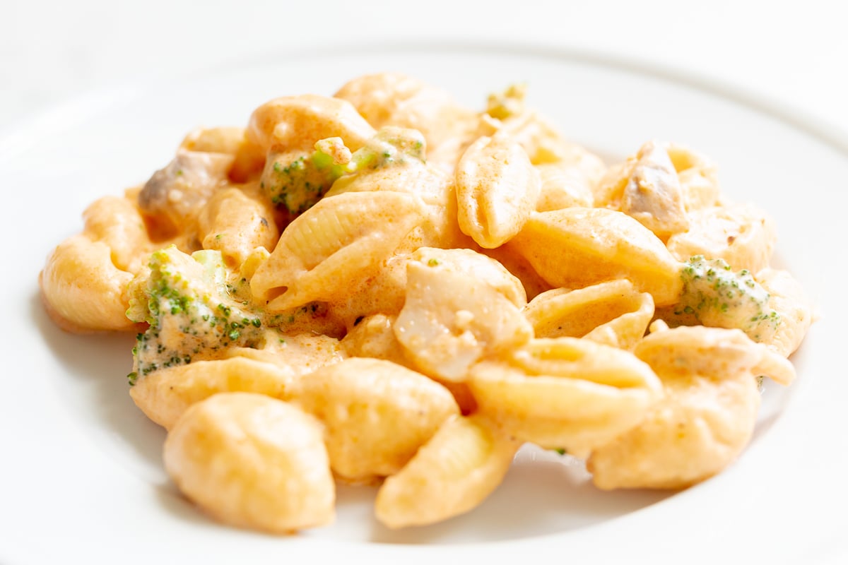 A white plate of pasta con broccoli.