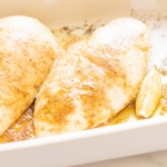 Baked chicken breasts in a white baking dish.