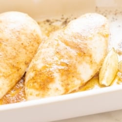 Baked chicken breasts in a white baking dish.