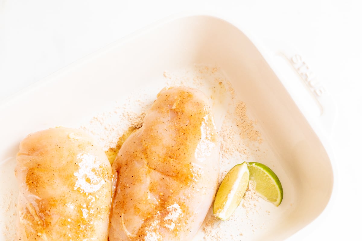 Chicken breasts in a white baking dish before baking.