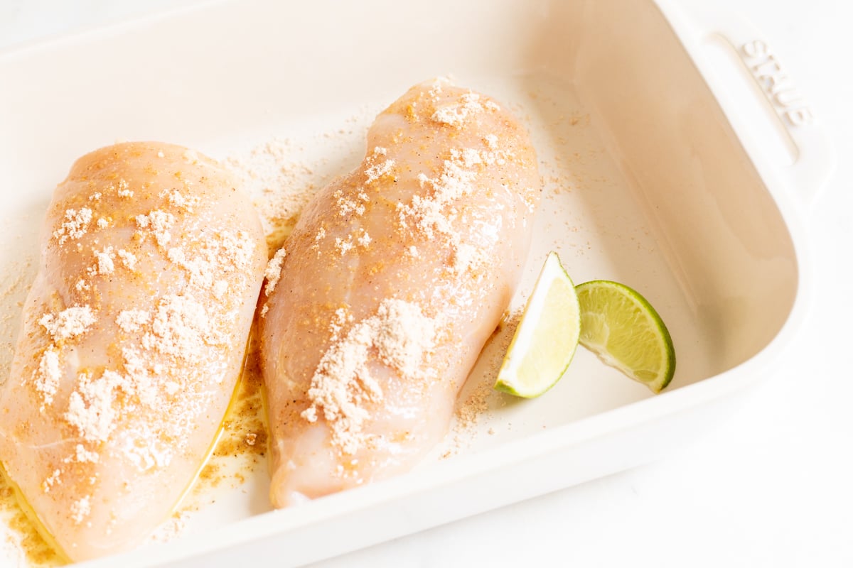 Chicken breasts in a white baking dish before baking.