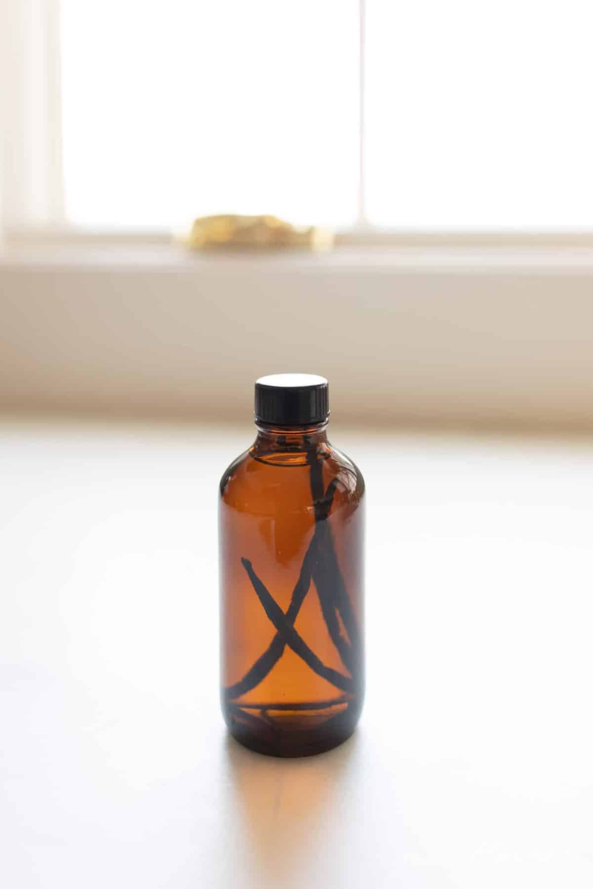 Homemade vanilla extract in an amber bottle on a white countertop. #homemadevanillaextract #vanilla #vanillabean