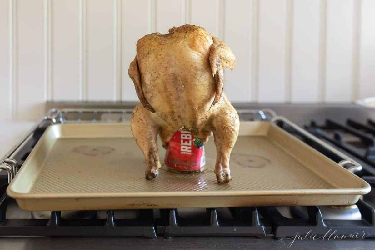 Whole chicken resting on a can of beer, on a gold sheetpan. #beercanchicken