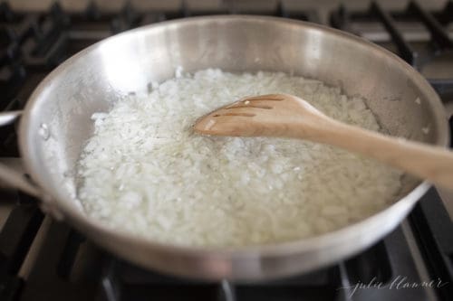 minced onion in a skillet with a wood spoon