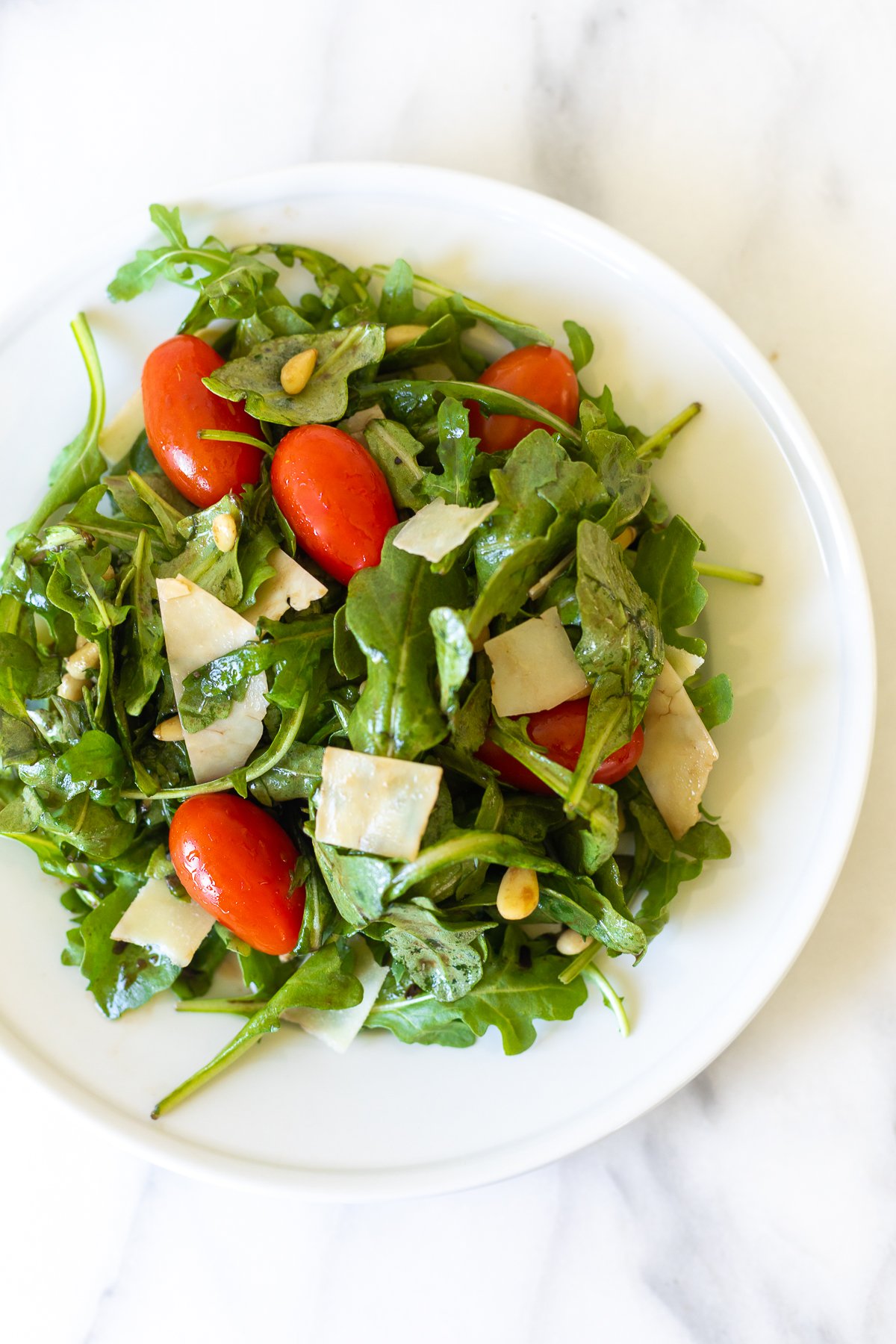 A white plate with insalata mista and a gold fork.