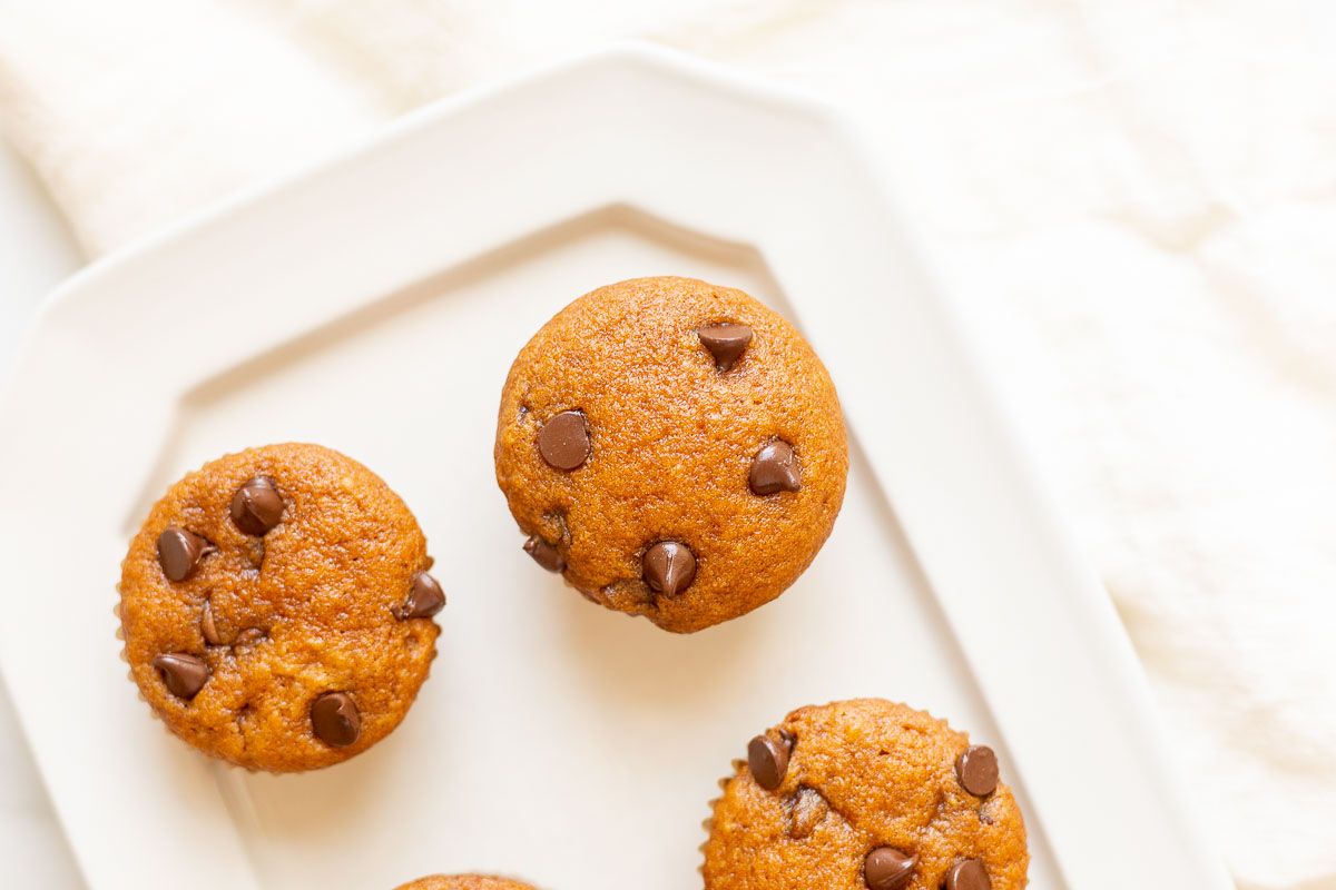 Mini pumpkin chocolate chip muffins on a white plate.