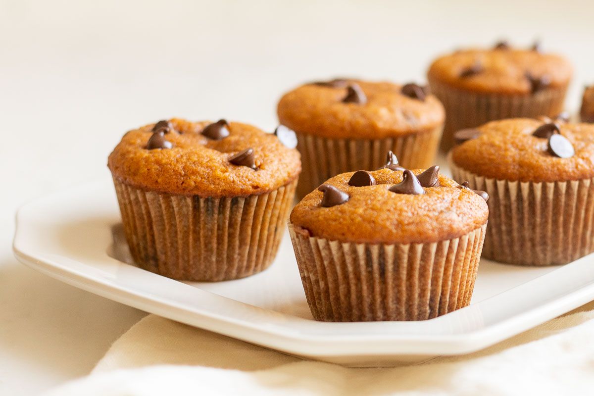 Mini pumpkin chocolate chip muffins on a white plate.