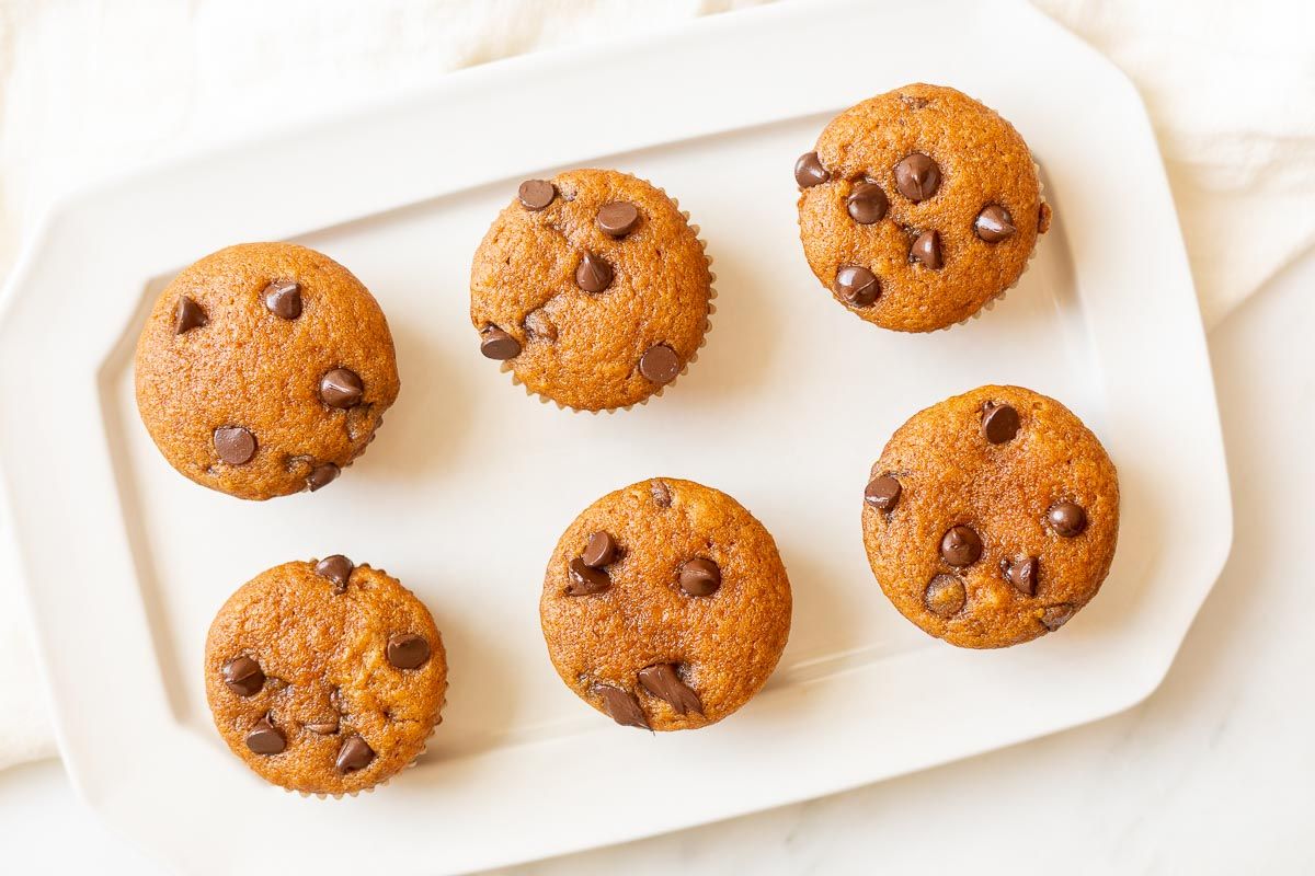 Mini pumpkin chocolate chip muffins on a white plate.