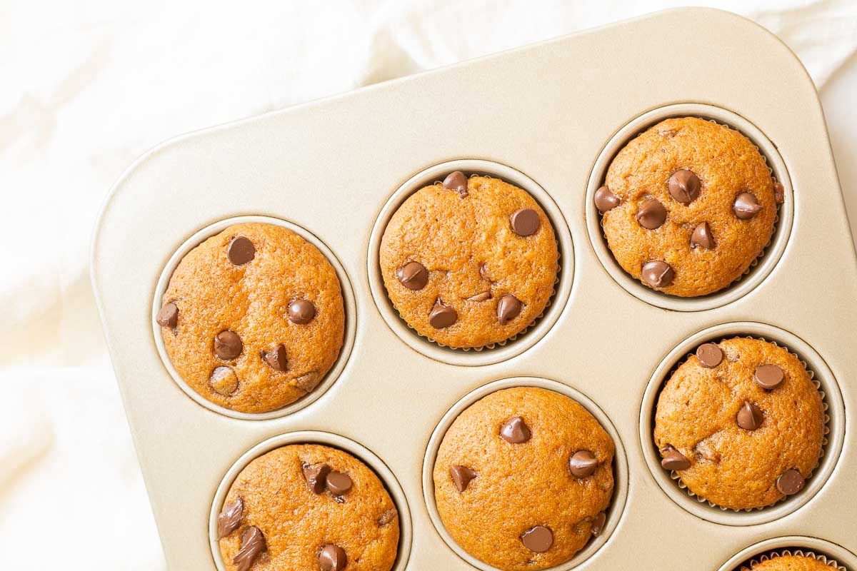 Mini pumpkin chocolate chip muffins in a gold muffin pan.