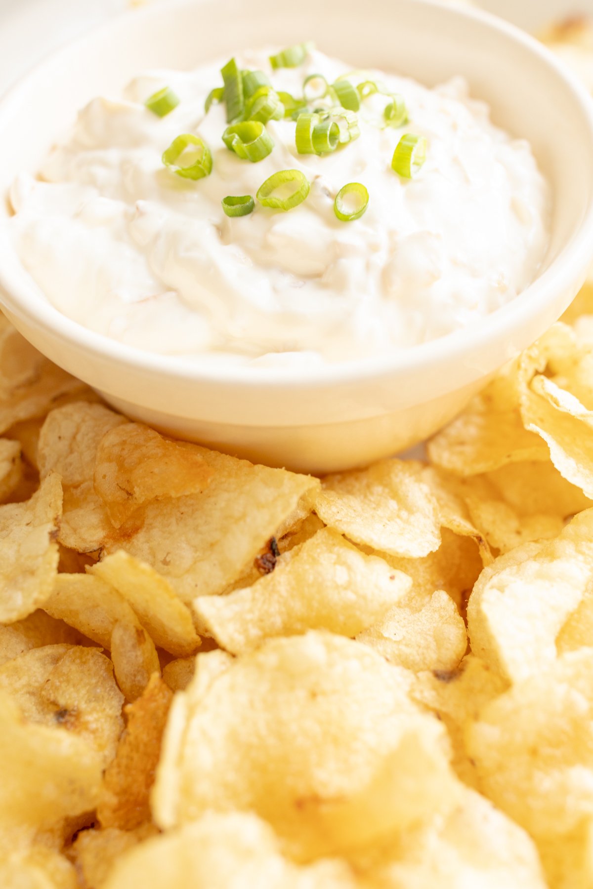 sour cream dip in a bowl surrounded by chips on a platter