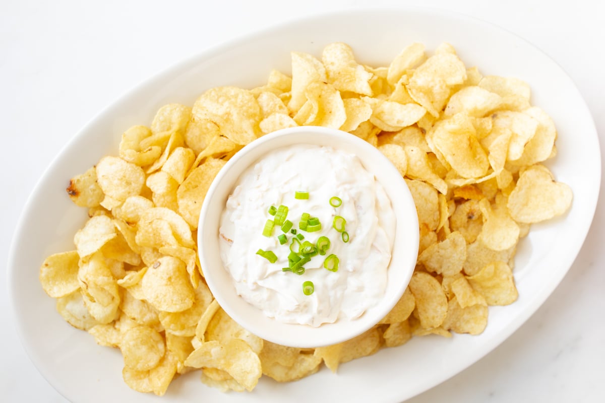 sour cream dip in a bowl surrounded by chips on a platter