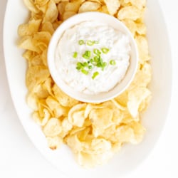 sour cream dip in a bowl surrounded by chips on a platter