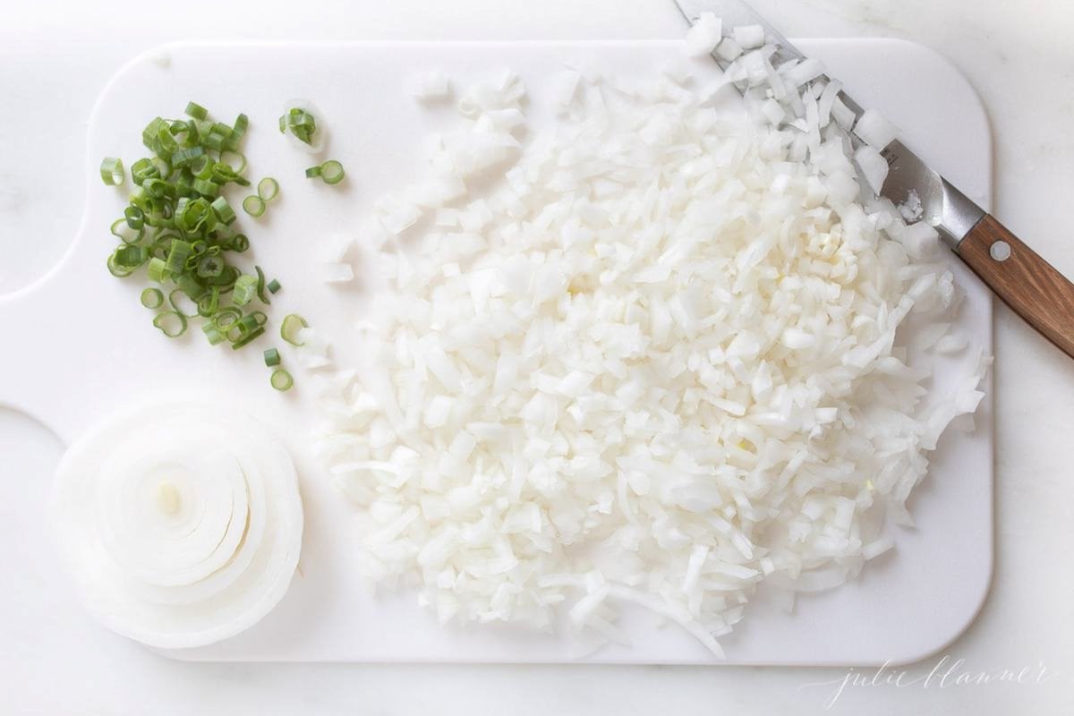 Chopped onions on a white cutting board.