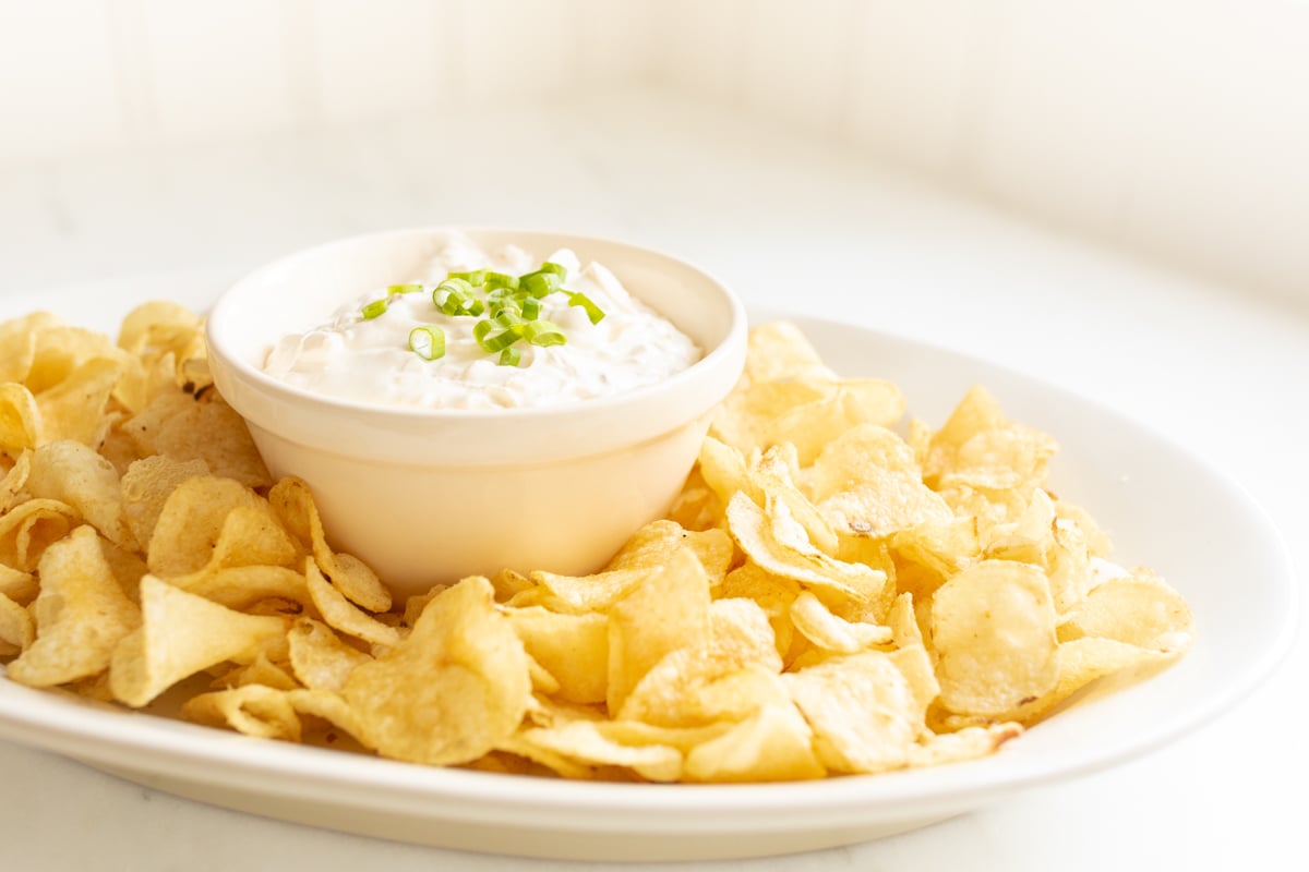 sour cream dip in a bowl surrounded by chips on a platter