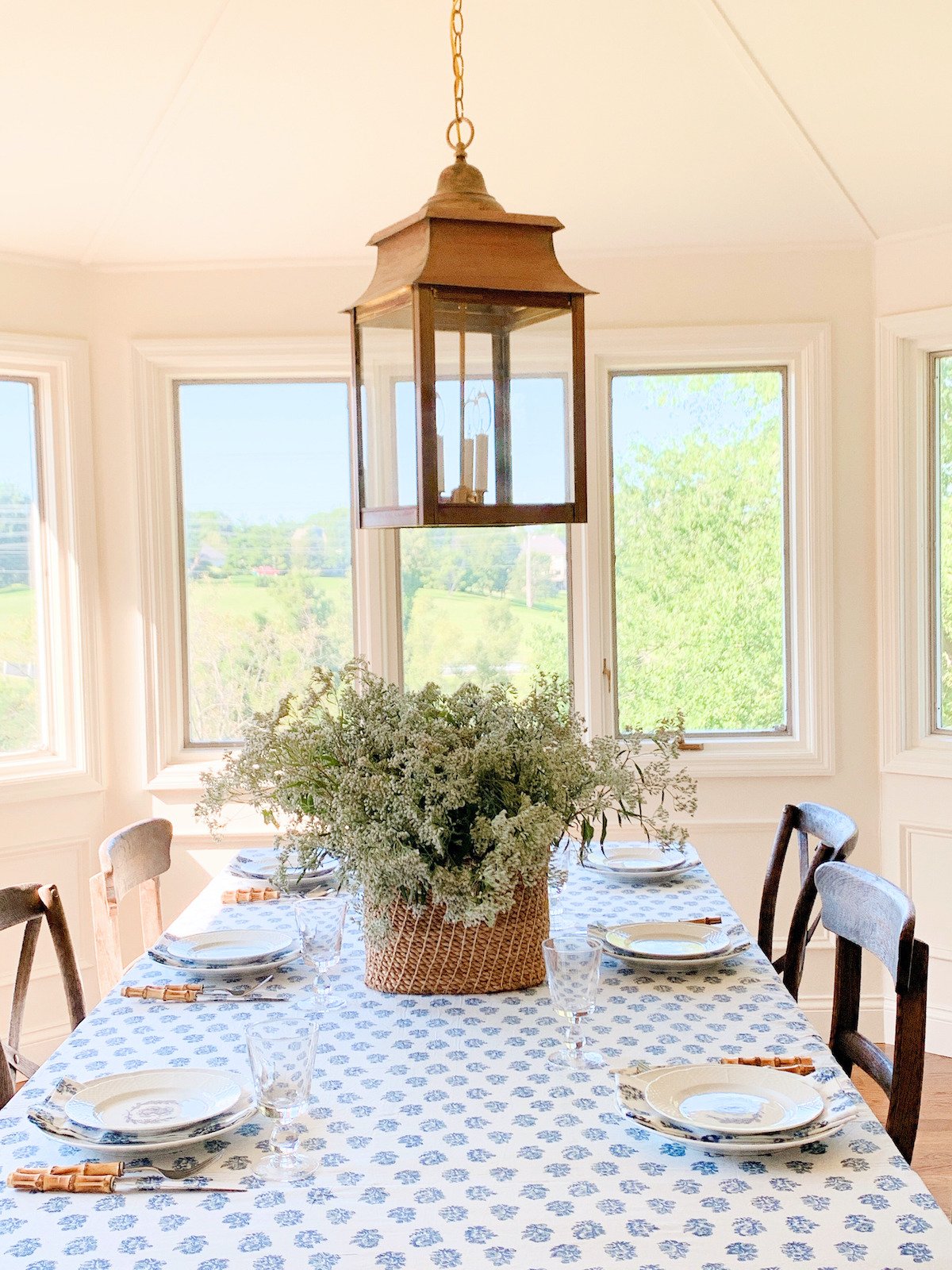 A blue and white block print tablecloth on a table surrounded by wood chairs.