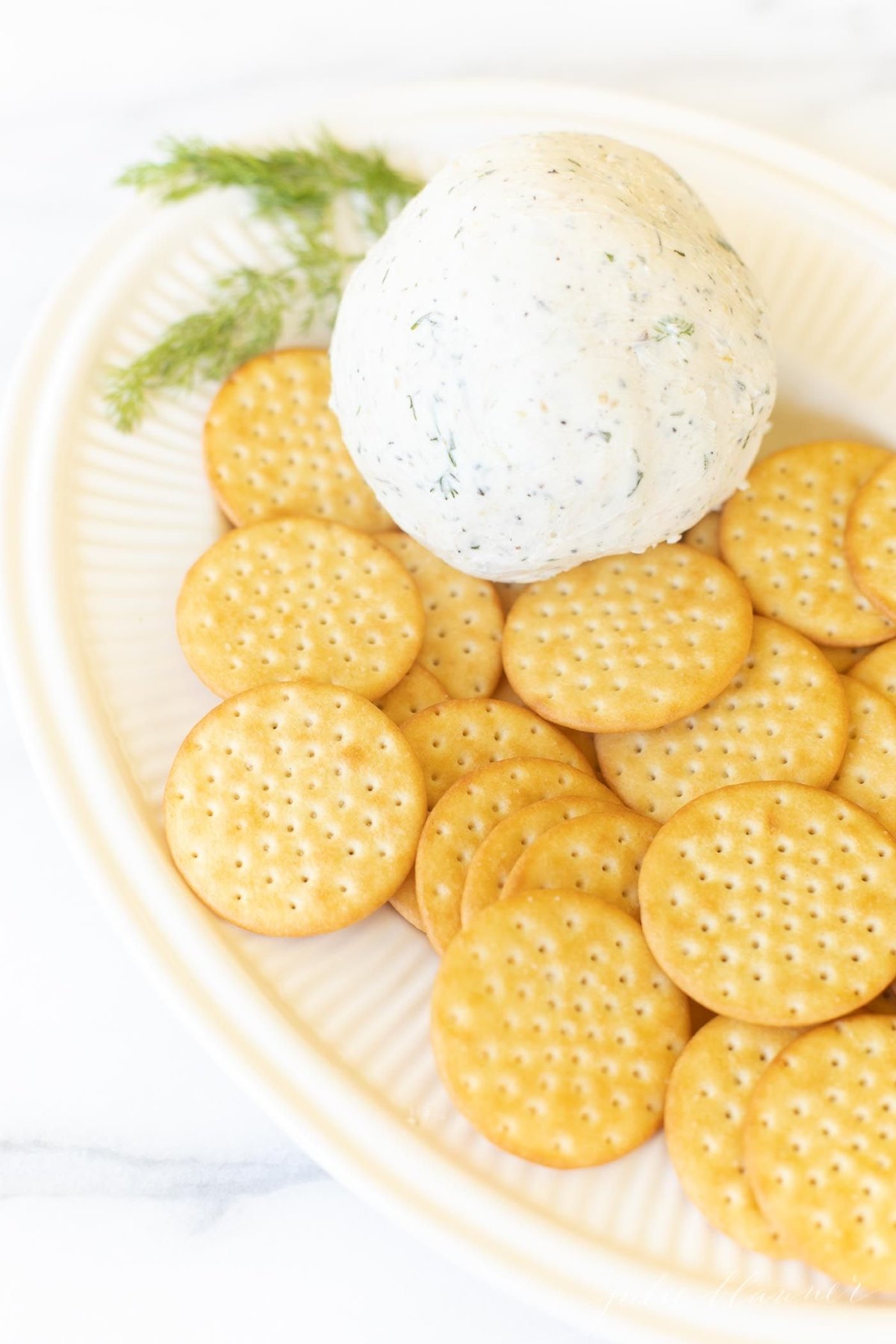 A white plate filled with crackers and homemade Boursin cheese.