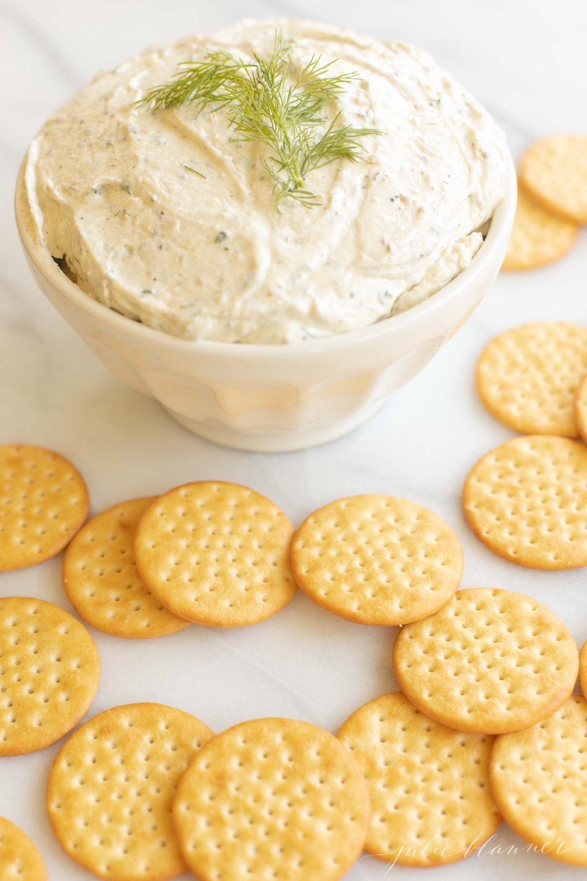 A white plate filled with crackers and homemade Boursin cheese.