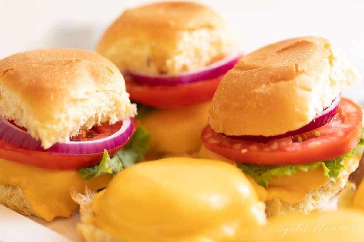 Sliders on a platter, with the front left missing a top bun. 