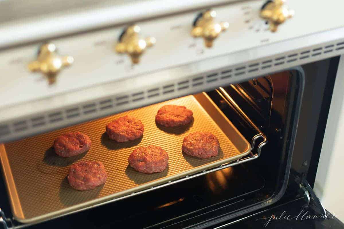 Burger patties on a baking sheet, going into the oven.