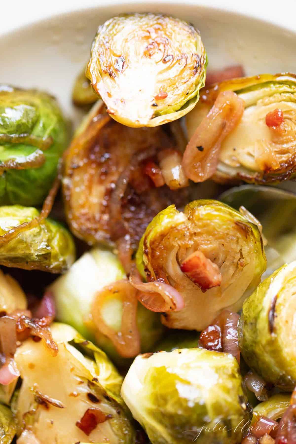 A close up of crispy brussel sprouts on a white plate.