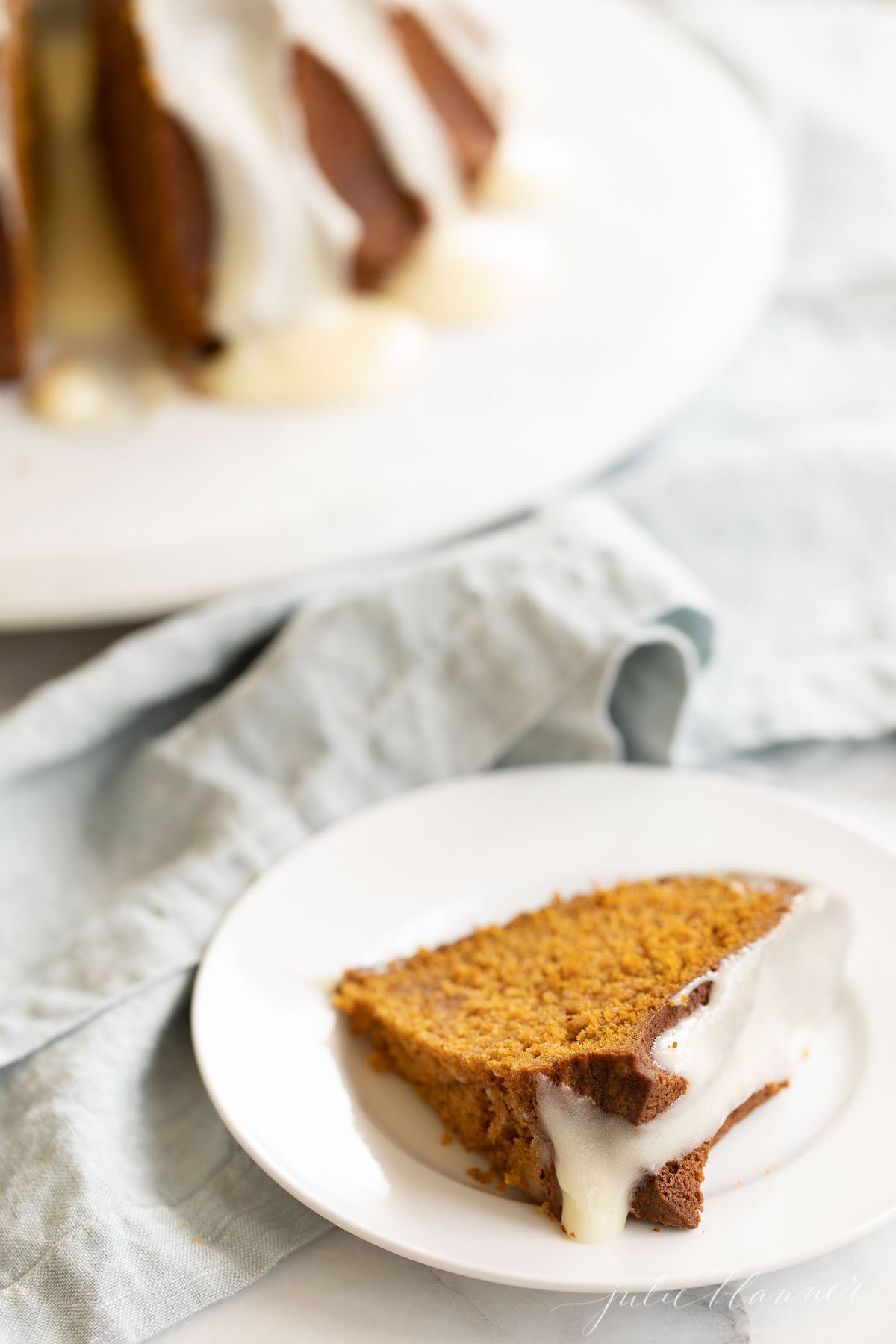 A slice of pumpkin bundt cake, with the full cake in the background.