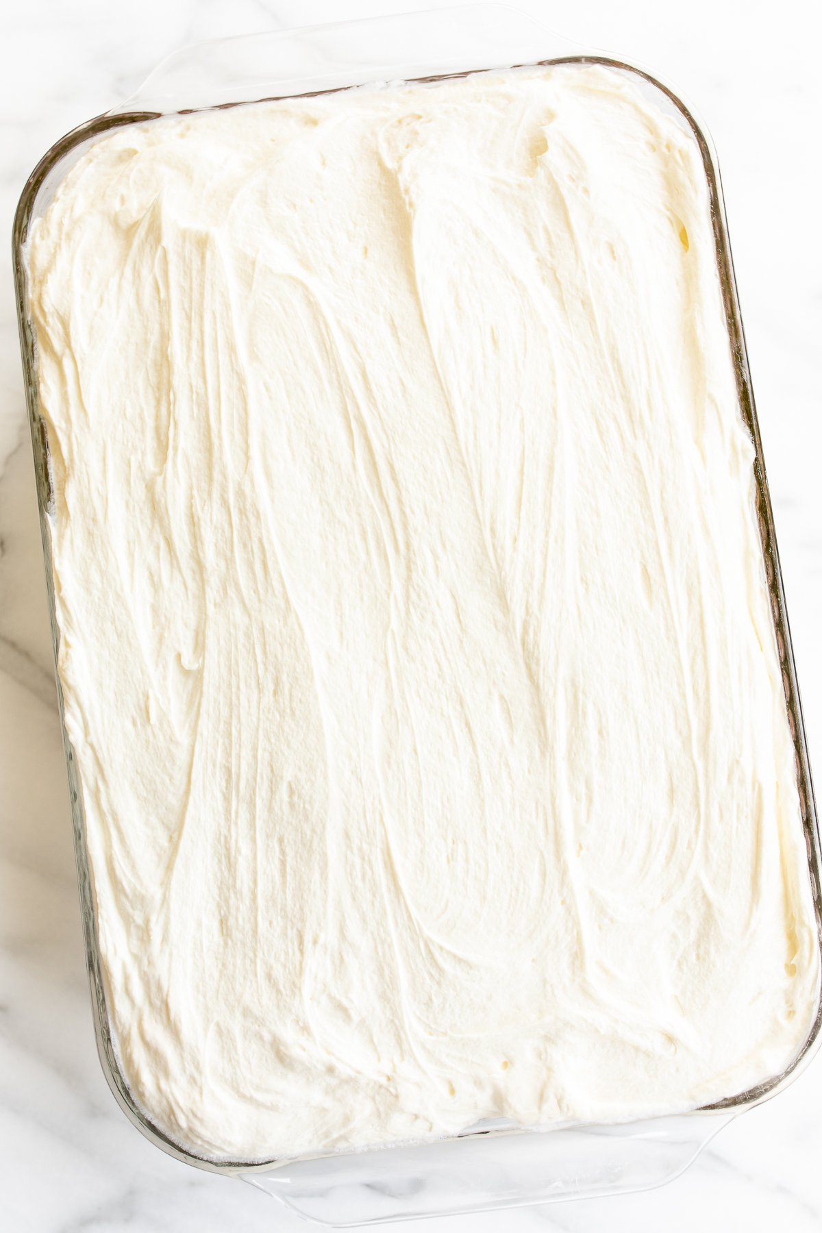 A pumpkin cake with frosting on a marble table.