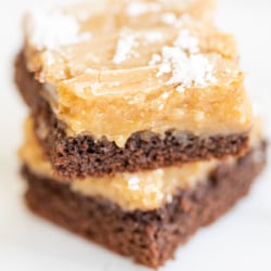 Two slices of ooey gooey butter cake stacked on a white surface.