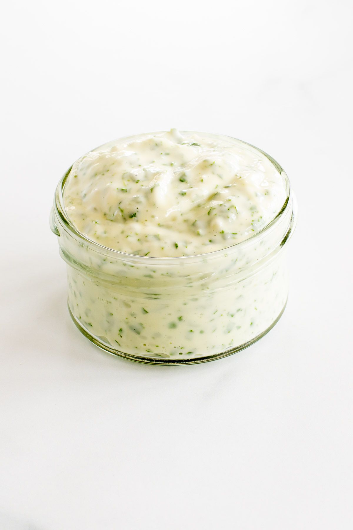 A small glass jar full of pesto aioli.