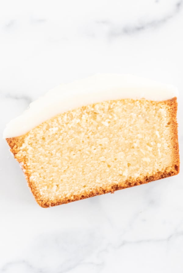 A slice of lemon pound cake on a marble surface.