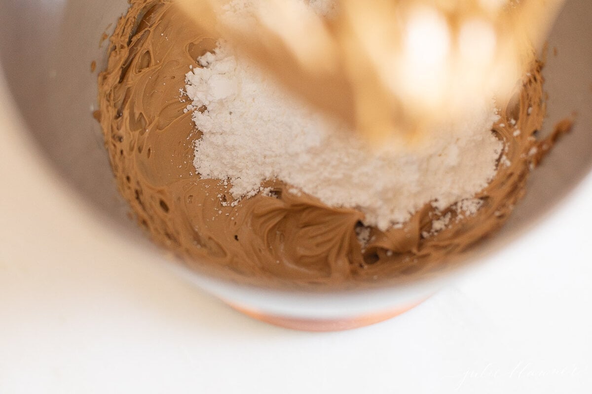 A whisk is being used to mix ingredients in a bowl for a Cookie Butter Cake recipe.