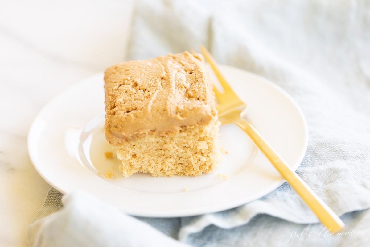 A piece of Cookie Butter Cake on a plate with a gold fork.