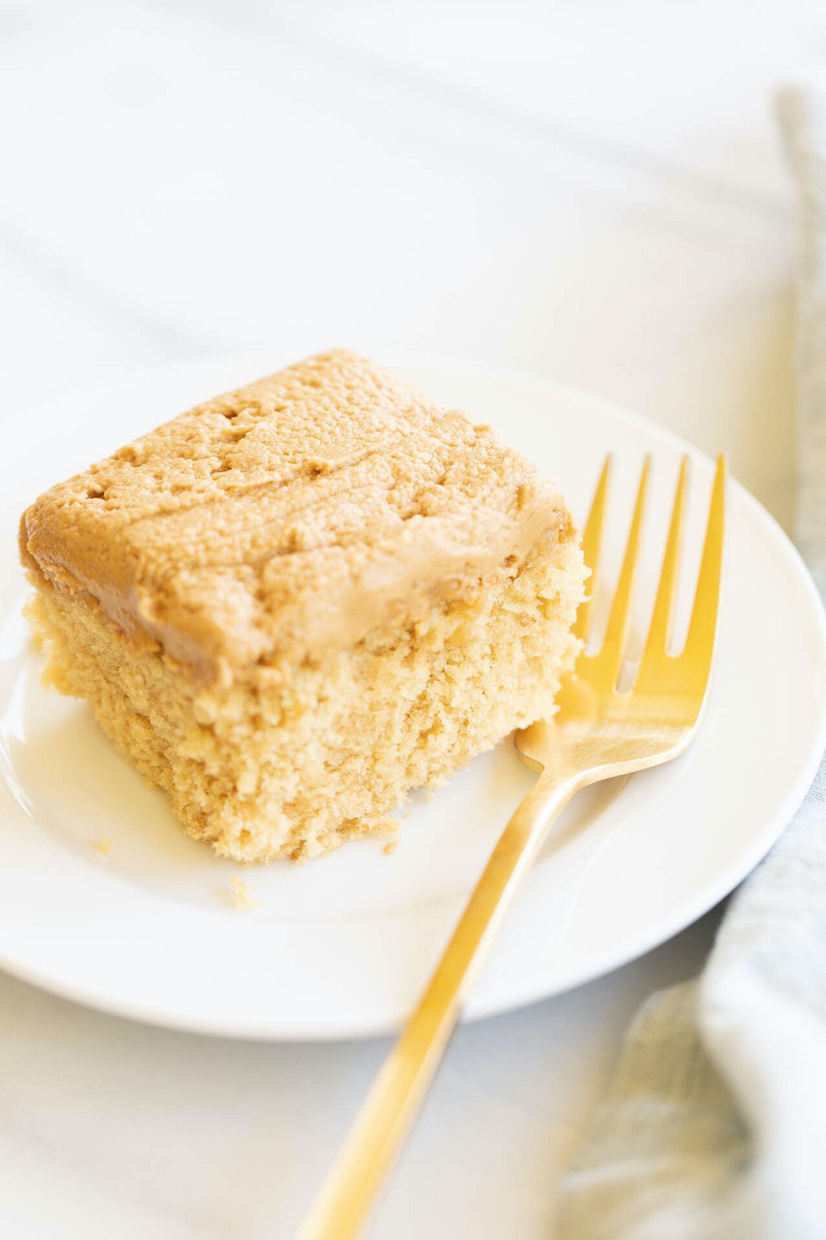 A slice of a Biscoff cake recipe on a plate with a gold fork.