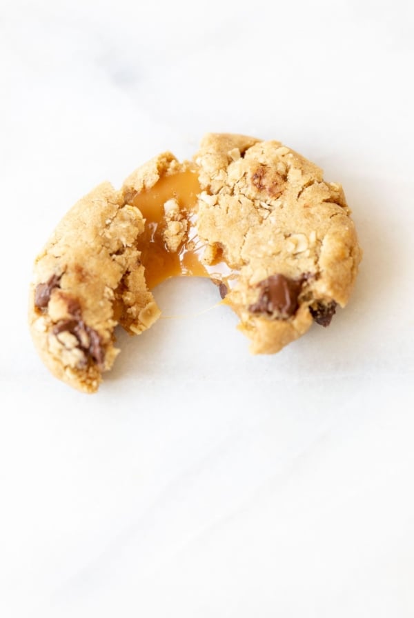 A carmelita cookie on a white marble surface, torn into two pieces.