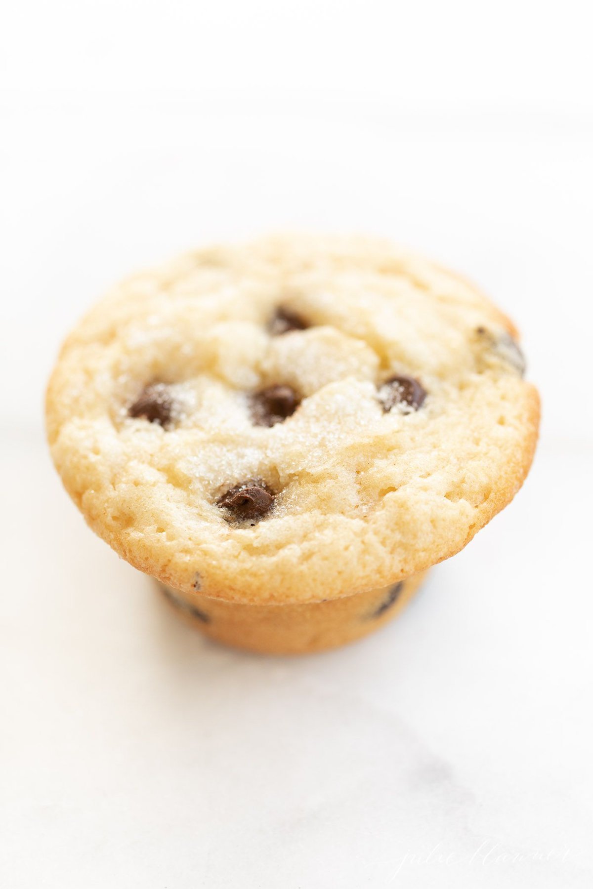 A chocolate chip muffin on a marble surface.