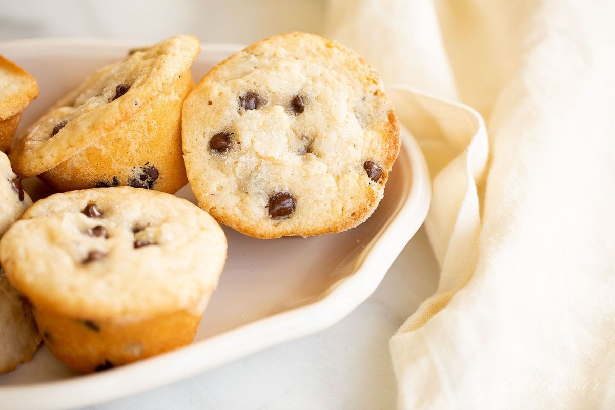 A white platter full of mini chocolate chip muffins.
