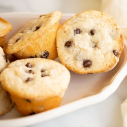 A white platter full of mini chocolate chip muffins.