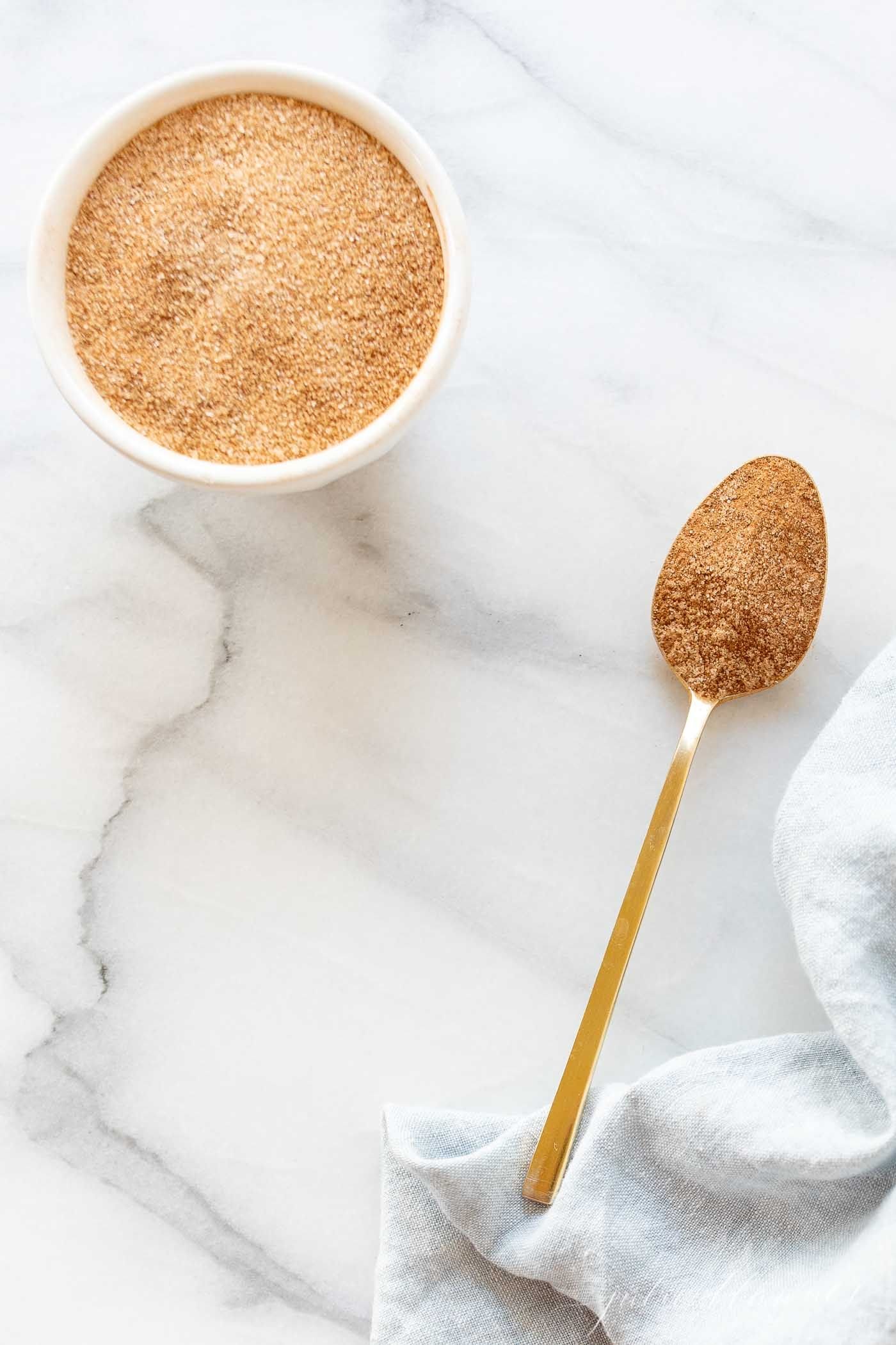 A bowl of cinnamon sugar with a gold spoon.