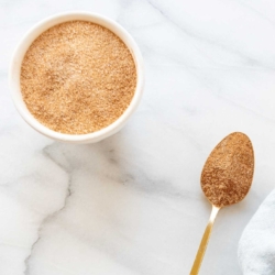 A bowl of cinnamon sugar with a gold spoon.