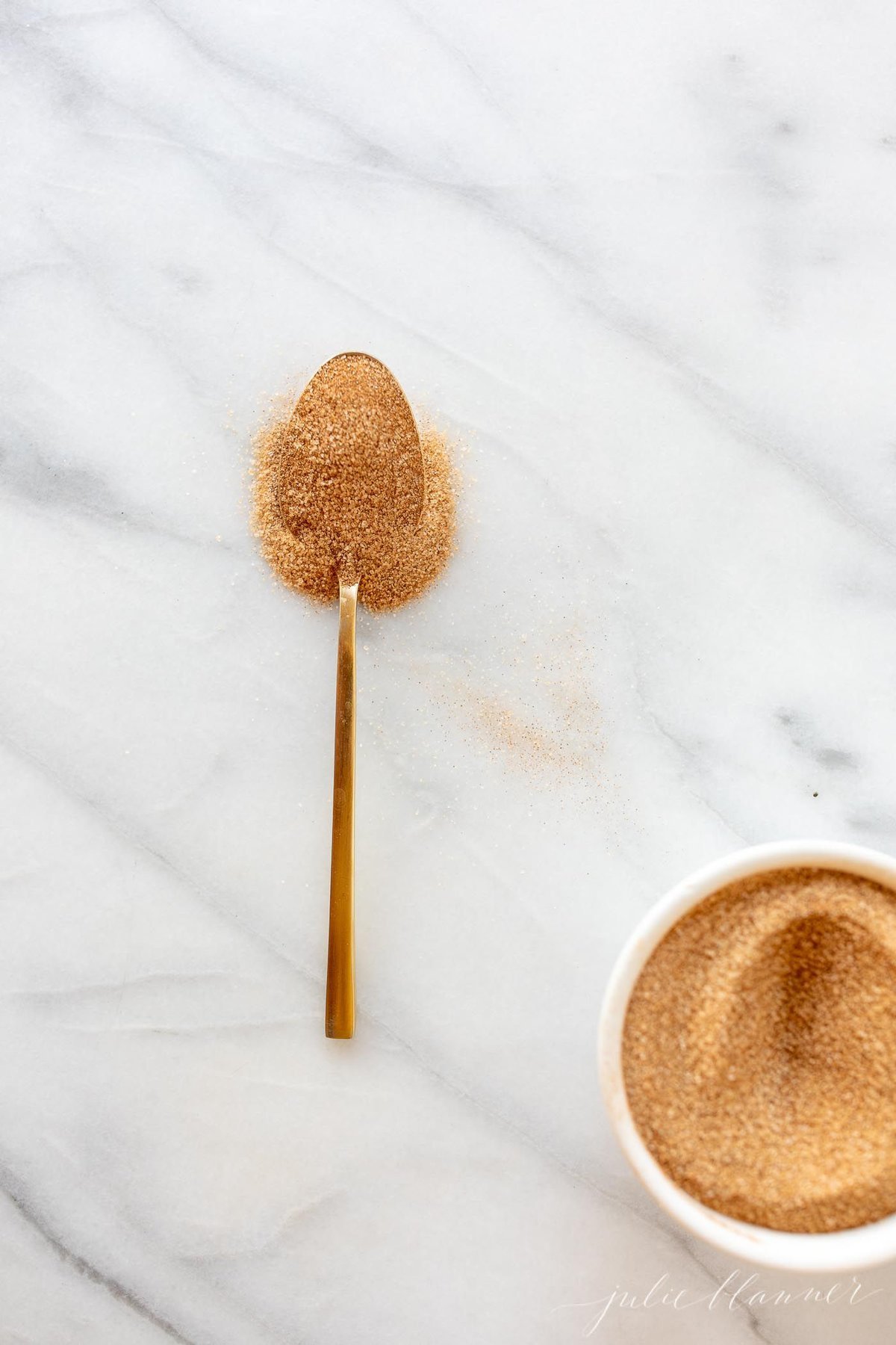 A bowl of cinnamon sugar with a gold spoon.