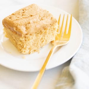 A slice of a Biscoff cake recipe on a plate with a gold fork.