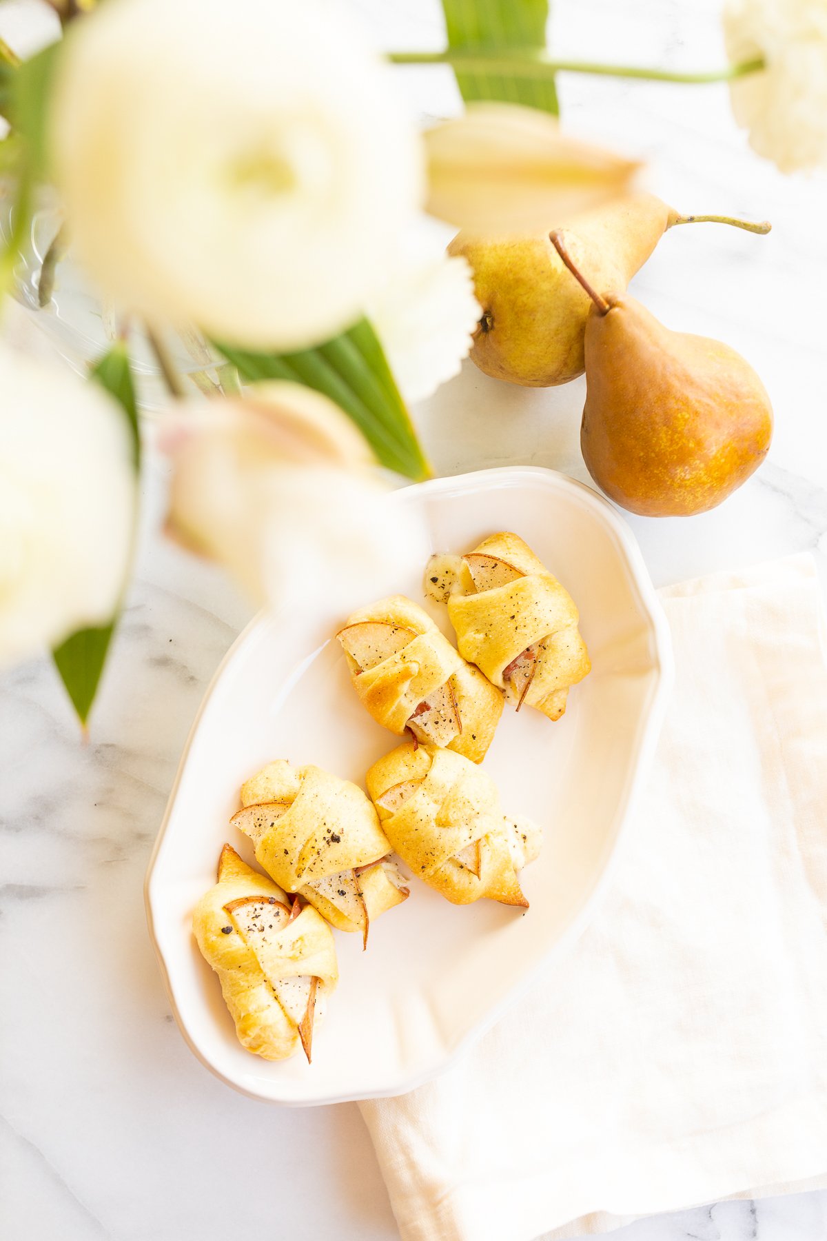 A plate adorned with pears and flowers is a charming display.