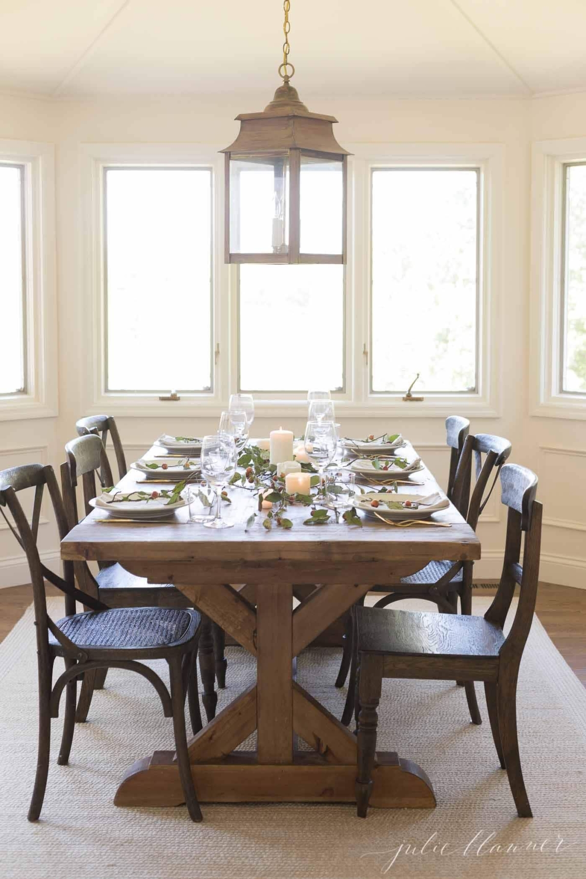 Farm table set for Thanksgiving dinner, candles and branches down the center.