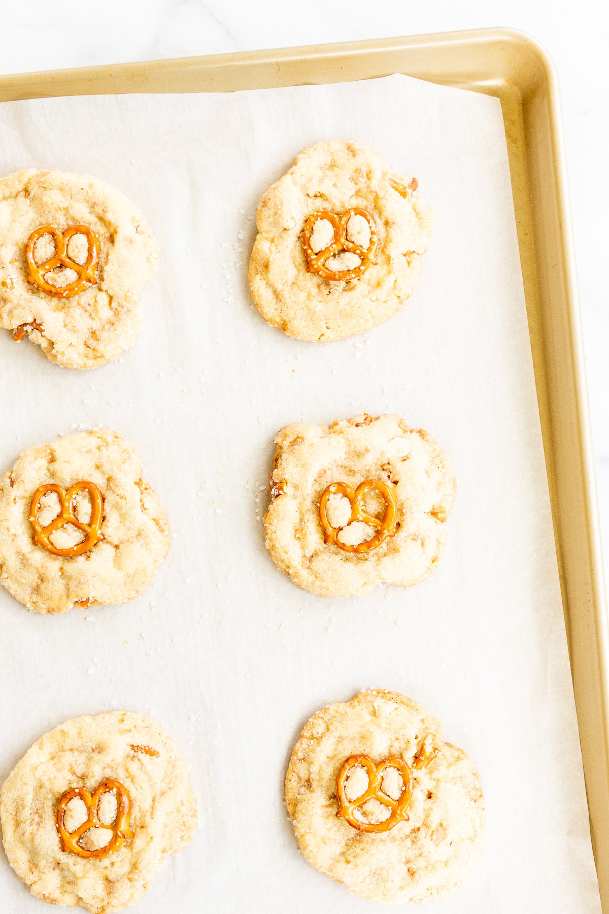 Kitchen sink cookies with pretzels, white chocolate and toffee on a baking sheet.