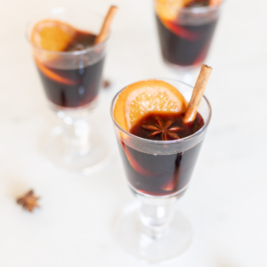 Glasses of mulled wine garnished with cinnamon sticks.